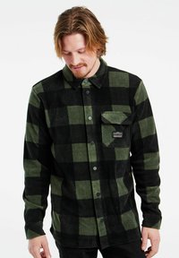 Groen en zwart geruite flanellen overhemd met een knoopsluiting, enkele borstzak en stofstructuur. Bevat zwarte knoopsluitingen en een logo-patch.