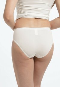 Witte katoenen hipsterondergoed met een gladde textuur, elastische tailleband en minimale naden, zichtbaar vanaf de achterkant.