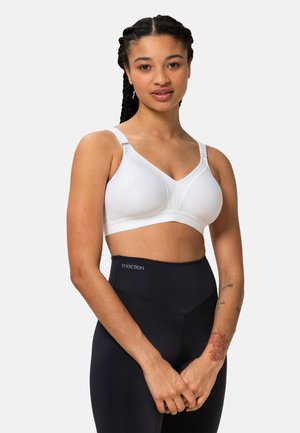 Weißer BH aus einem glatten, dehnbaren Stoff, mit gepolsterten Cups und verstellbaren Trägern. Kombiniert mit hoch taillierten schwarzen Leggings mit einem Logo.