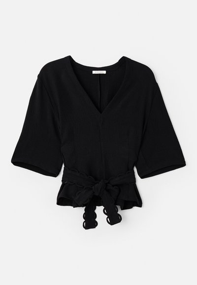 Black wrap top with a V-neck, short sleeves, and a knotted tie at the waist. Features textured fabric and scalloped trim on the tie.