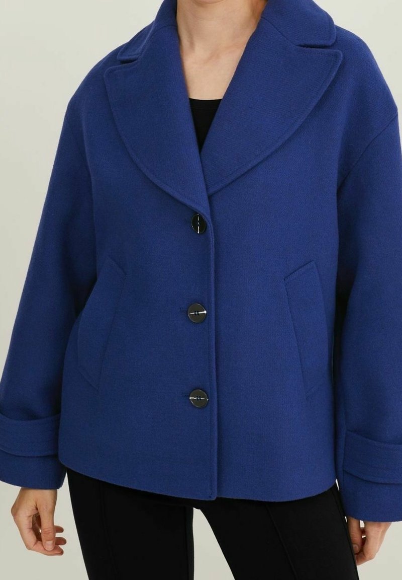 Blå jacka i ullblandning med bred krage, framknäppning med knappar, två sidofickor och avslappnade ärmar.