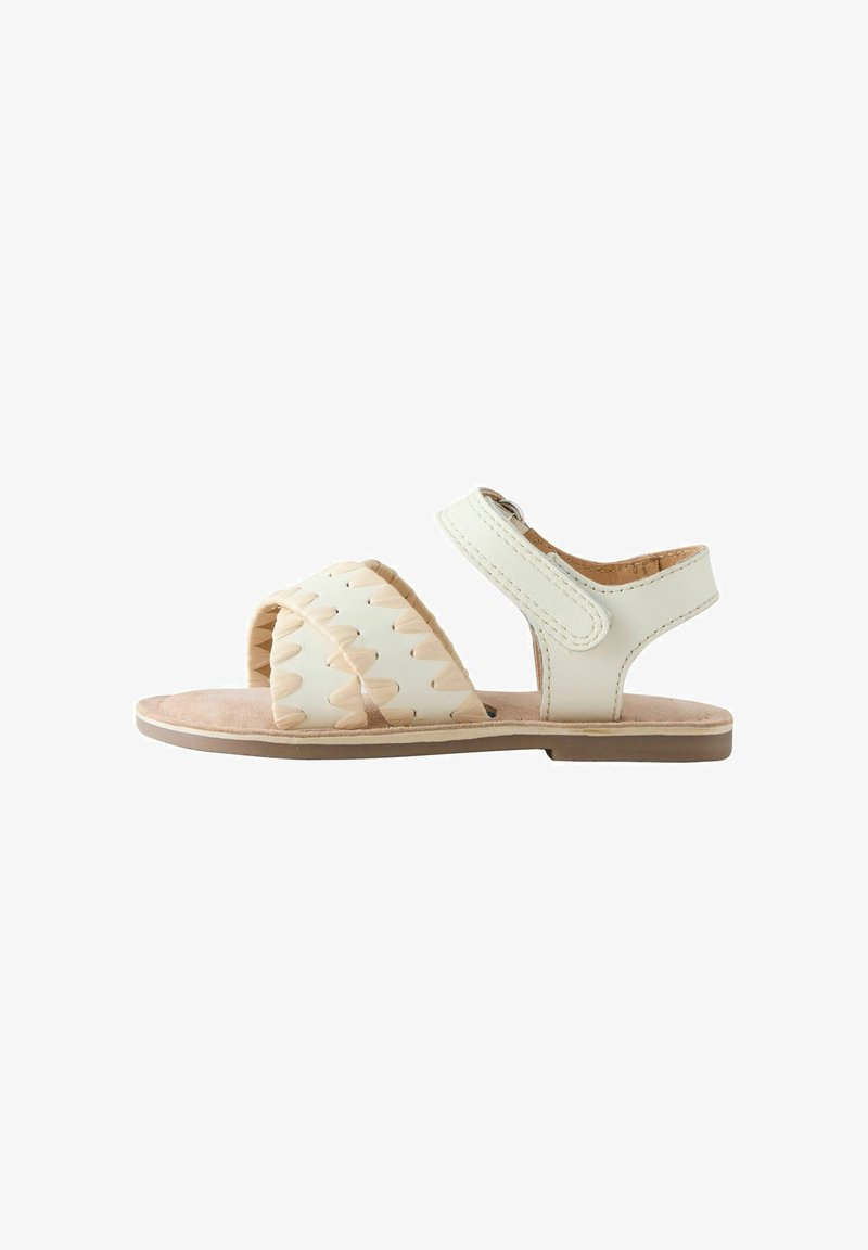 Sandale plate beige avec bride tressée à l'avant, bride de cheville avec fermeture Velcro et semelle rembourrée.