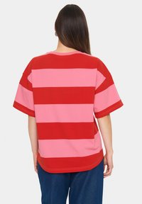 Rød og pink stribet T-shirt med korte ærmer, en rund halsudskæring og en afslappet pasform. Stoffet ser blødt og letvægtsagtigt ud.