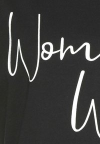 Camiseta de algodón negra con texto blanco que dice "Mujer" en una fuente cursiva, con una textura suave y un diseño informal.