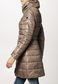 Puchowa kurtka w kolorze taupe, pikowana, z wysokim kołnierzem, guzikami oraz zmniejszoną talią. Posiada błyszczące wykończenie i średniej długości krój.