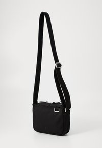 Borsa a tracolla nera realizzata in tessuto, con forma rettangolare, chiusura con zip e tracolla regolabile con fibbia metallica.