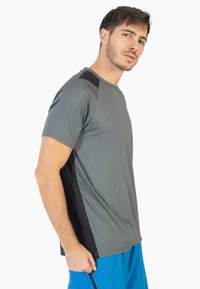 Camiseta deportiva gris de manga corta, con detalles en negro en los hombros y los lados, hecha de un tejido ligero y suave.