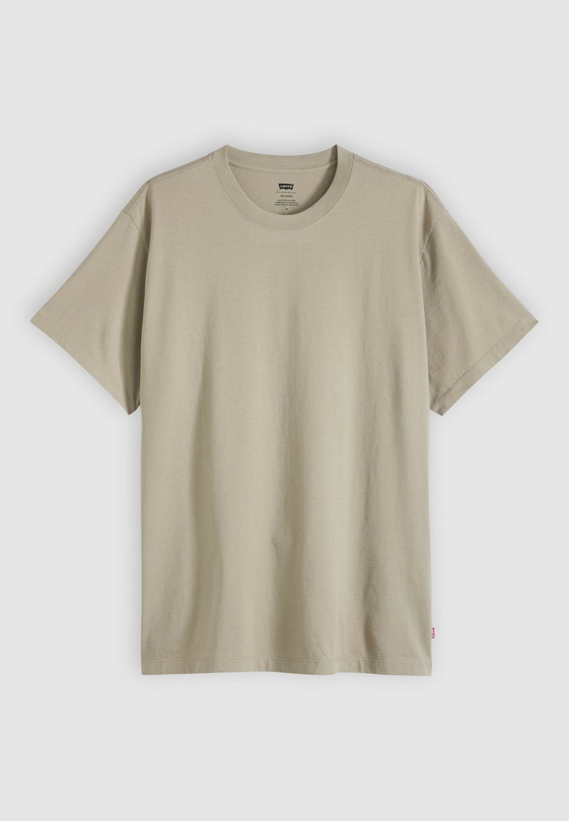T-shirt beige semplice a maniche corte con scollo rotondo, stesa su uno sfondo grigio chiaro, con un piccolo tag rosso sull'orlo inferiore.