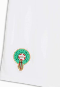 Emblème brodé de la Fédération Royale Marocaine de Football en vert, rouge, blanc et or sur tissu blanc.