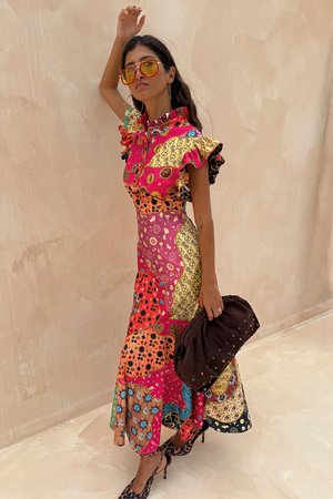 Kleurrijke, patchwork maxi-jurk met gerimpelde mouwen, bloem- en geometrische patronen, een ronde kraag en gecombineerd met een bruine clutch.