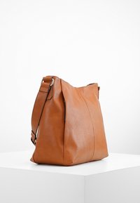 Borsa a tracolla in pelle marrone con superficie texture, dotata di una cintura singola e dettagli di cucitura sui lati.