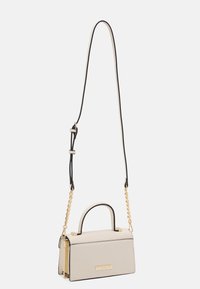Strukturalna torba na ramię w jasnobeżowej skórze z czarną lamówką, wyposażona w górny uchwyt, regulowany łańcuszkowy pasek oraz złote elementy ozdobne.