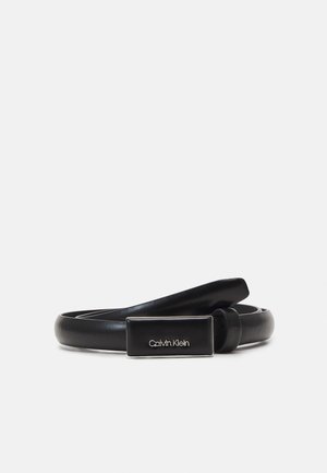 Sort læderbælte rullet sammen med rektangulær metalspænde med indgraveret Calvin Klein-logo, vist på ensartet lys baggrund.