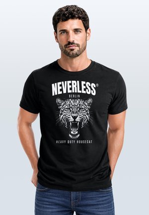 Man with dark curly hair and beard wearing black T-shirt with roaring leopard face and text "NEVERLESS BERLIN HEAVY DUTY HOUSECAT"