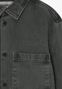 Jachetă din denim gri cu guler clasic, închidere cu butoane și un singur buzunar pe piept, având un model texturat al țesăturii.