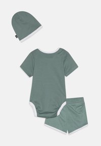 Bodysuit en coton vert à manches courtes avec bord blanc, associé à un short vert assorti et un bonnet coordonné. Texture lisse, design décontracté.