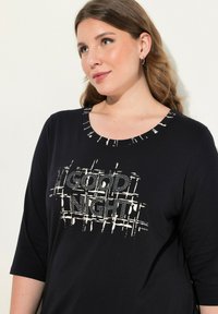 Czarny długi rękaw top z okrągłym dekoltem, z napisem "DOBREJ NOCY" w białym kolorze, z siatkowatym wzorem i akcentami z cyrkonii.