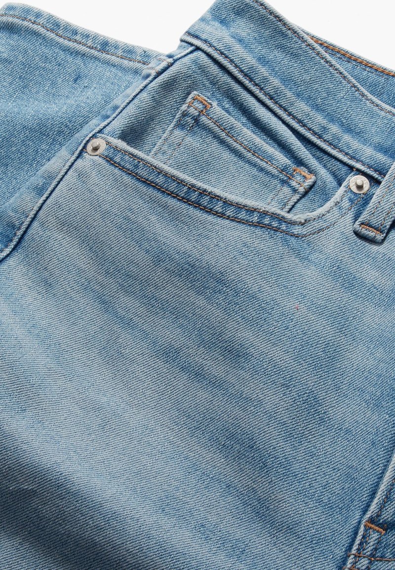 Helle blaue Denim-Jeans mit einer glatten Textur, ausgestattet mit einer Gesäßtasche und kontrastierenden orangefarbenen Nähten an der Taille und den Nähten.
