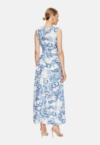Abito maxi in tessuto bianco con motivi floreali e paisley blu. Design senza maniche con un corpetto attillato e una gonna fluente.