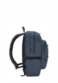 Sac à dos bleu marine avec plusieurs compartiments zippés, bretelles rembourrées, boucle latérale et poignée supérieure en boucle, présenté de profil.