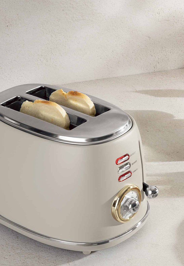Toaster s krémovým tělem, nerezovými akcenty, dvěma otvory a dekorativním knoflíkem s nastavením teploty a funkčními tlačítky.
