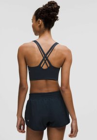 Jūras zila sporta krūšturis ar krustveida aizmuguri un saskaņoti tumši šorti ar elastīgu jostu un diskrētu logo detaļu.