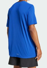 Maglietta sportiva blu a maniche corte, realizzata in tessuto leggero. Presenta una scollatura rotonda e un'etichetta con logo vicino all'orlo.