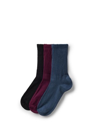 Drie paar geribbelde enkelsokken in zwart, bordeauxrood en marineblauw, netjes opgestapeld op een witte achtergrond.