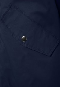 Navy blue textile featuring a diagonal cut pocket with a silver snap button accent, smooth matte texture and subtle stitching details.