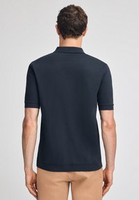 Marinblå polo-t-shirt med korta ärmar och platt krage, mjukt material, figursydd passform, med en subtil nederkant och utan synliga mönster.