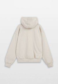 Jasno beżowy hoodie z kangurzą kieszenią, elastycznymi mankietami i regulowanym kapturem. Wykonany z miękkiego, teksturowanego materiału o luźnym kroju.