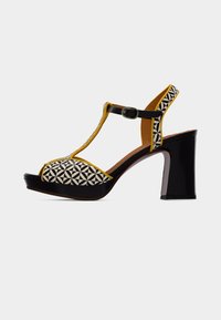 Μαύρο και κίτρινο σανδάλι με ψηλό τακούνι, με γεωμετρικό μοτίβο στην περιοχή των δαχτύλων, σχέδιο με λουρί σε σχήμα Τ και ρυθμιζόμενο λουρί αστραγάλου· γυαλιστερό φινίρισμα.