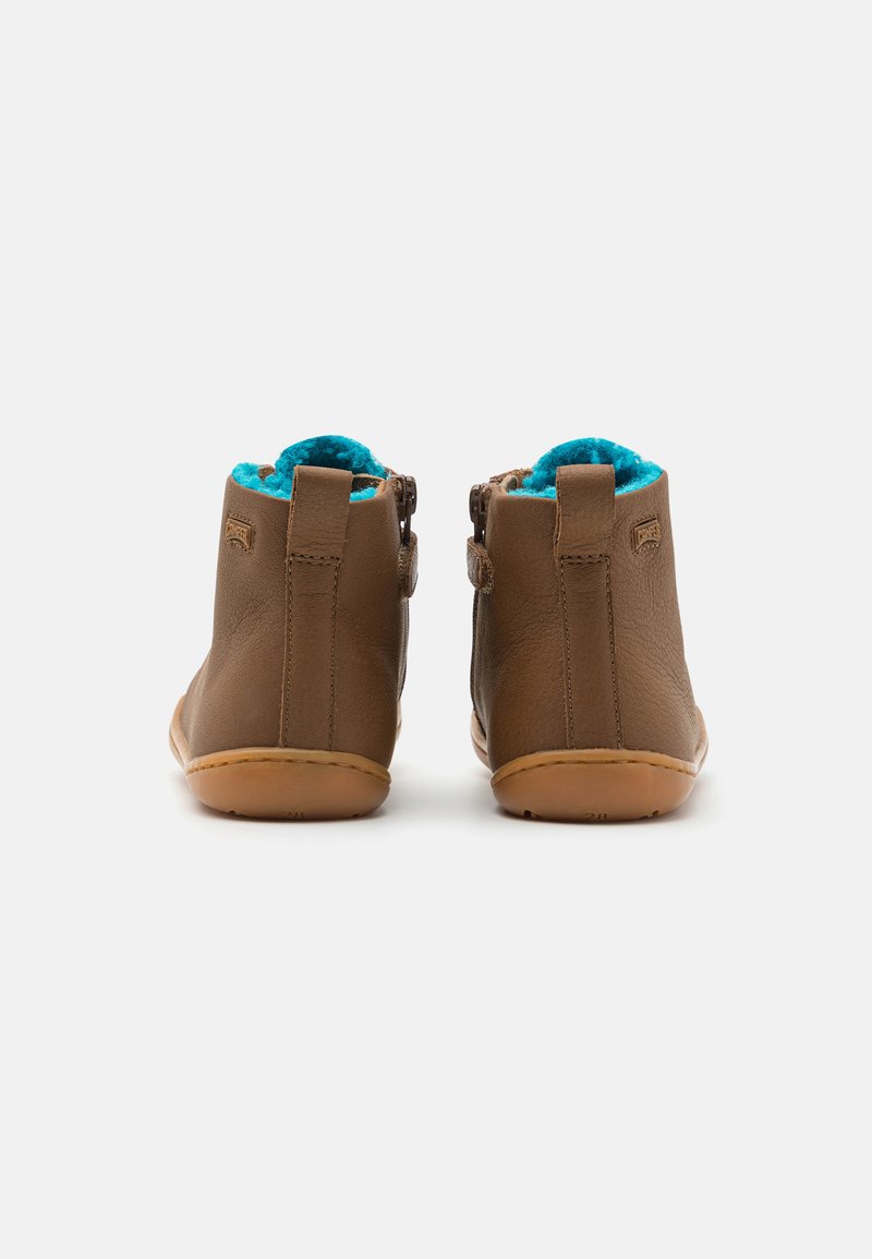 Botas de cuero marrón hasta el tobillo con forro de forro polar turquesa y suela de goma; cuentan con cremalleras y un detalle de logotipo en el costado.