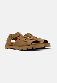 Brown suede sandals with a woven strap design, open toe, adjustable buckle, and a textured rubber sole for grip.