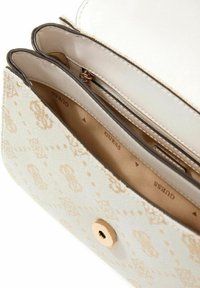 Sac à main couleur crème avec un motif embossé subtil, doté d'une fermeture à pression dorée, d'une poche zippée et d'une doublure intérieure lisse.