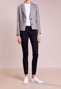 Grå rutigt kavaj med notch-lapel, knappstängning, i kombination med en vit t-shirt, svarta skinny jeans och vita sneakers.