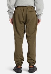 Olivgröna joggers med elastisk midja, elastiska mudd, ett bakfack och en slät, lätt tygstruktur.