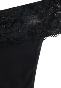 Schwarze Lingerie mit floraler Spitzenbehandlung am oberen Rand vor einem weißen Hintergrund.