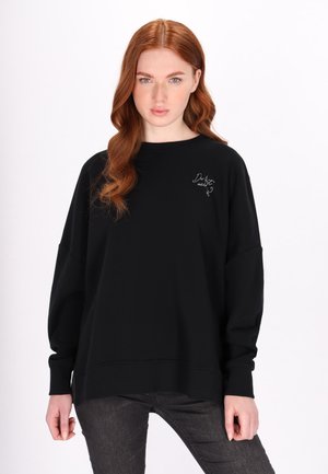 Felpa nera oversize in cotone, con scollatura e polsini a costine, caratterizzata da una piccola scritta bianca sul davanti.