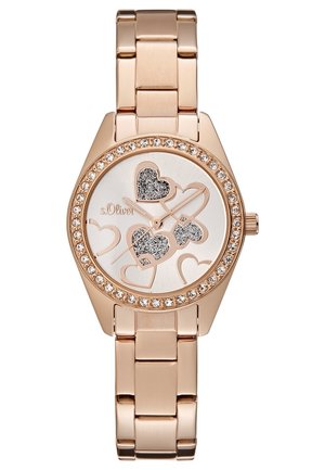 Roségouden polshorloge met een met kristallen bezette lunette, decoratieve glinsterende hartmotieven op een witte wijzerplaat en een geschakelde metalen armband.
