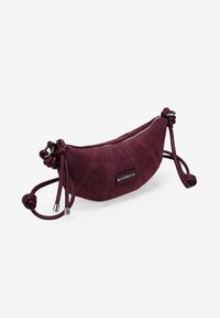 Bolso de gamuza burdeos con forma curvada, cierre de cremallera y detalles de cuero anudado. Presenta una etiqueta de marca en el lateral.