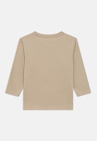 Μπεζ μακρυμάνικη μπλούζα με στρογγυλή λαιμόκοψη, τοποθετημένη επίπεδα ώστε να φαίνεται η πίσω πλευρά με απλή ραφή στα μανίκια και το στρίφωμα.