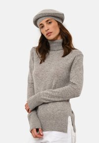 Šedý rolák se žebrovanými manžetami a spodním lemem, s postranními rozparky pro uvolněný střih. K tomu se hodí šedá čepice typu beret.