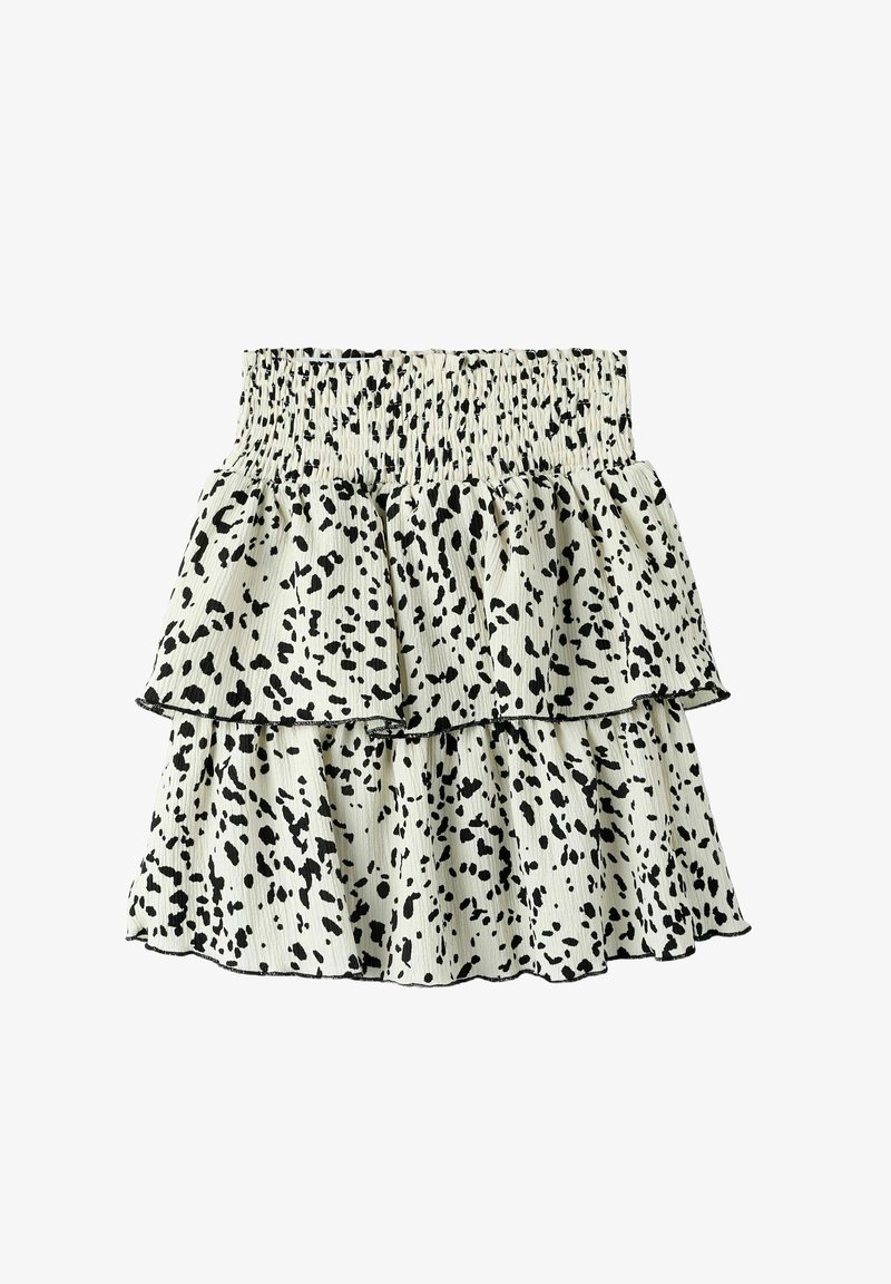 Jupe en tiered avec un waistband élastique, présentant un tissu crème avec des motifs de taches noires. Design léger et fluide.