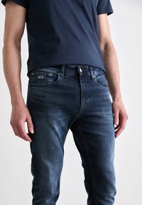 Mörkblå denimjeans med smal passform, med fem fickor, kontrasterande sömmar och en liten logotag på bakfickan.