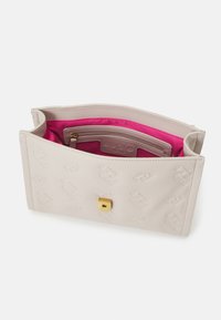 Borsa a mano beige chiaro in pelle liscia, con una chiusura dorata e una foderatura interna di un vivace rosa con un'etichetta del logo.