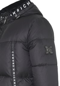 Giubbino pèntoso nero con zip frontale, stampa del logo sul colletto e una toppa sulla manica. Presenta una texture liscia e lucida.