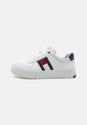 Witte sneaker met geperforeerde textuur, marineblauwe en rode strepen, rubberen zool en vetersluiting. Verstevigde hiel voor extra ondersteuning.