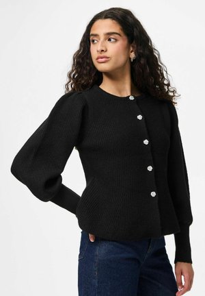Cardigan en tricot noir à côtes, avec un col rond, des manches bouffantes et cinq boutons en forme de fleur argentés sur le devant.
