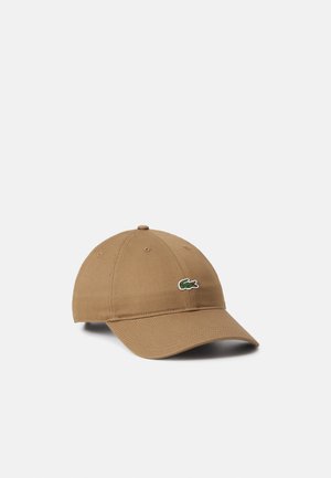 Gorra de béisbol de algodón marrón con visera curvada y logotipo de cocodrilo verde bordado en la parte delantera. Cuenta con seis ojales de ventilación y parte trasera ajustable.